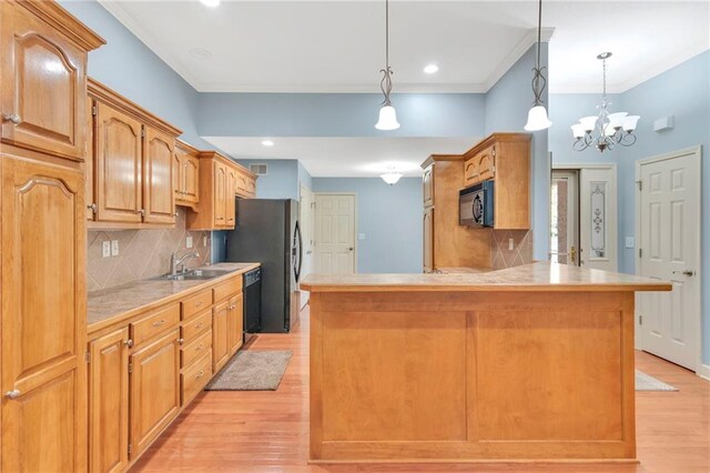 kitchen featuring sink, black appliances, pendant lighting, an inviting chandelier, and light hardwood / wood-style floors