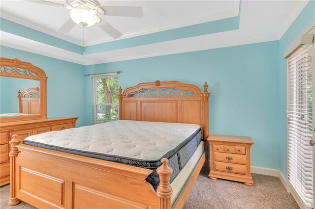 bedroom featuring crown molding, light colored carpet, a tray ceiling, and ceiling fan