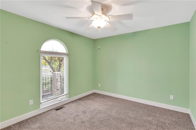 carpeted empty room featuring ceiling fan and a wealth of natural light