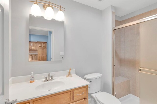 bathroom featuring toilet, a shower with shower door, and vanity