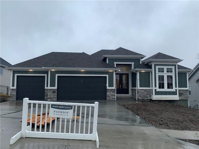 prairie-style home with driveway, stone siding, french doors, board and batten siding, and a garage