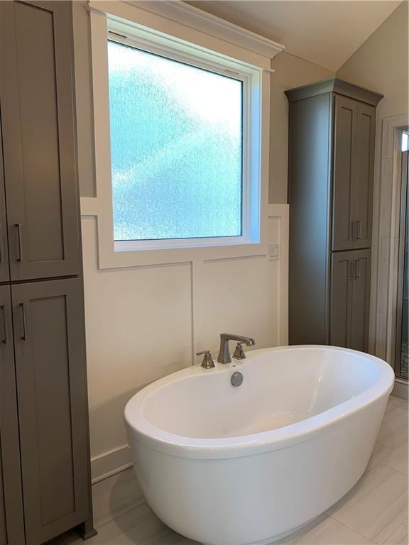 bathroom featuring a wealth of natural light and a soaking tub