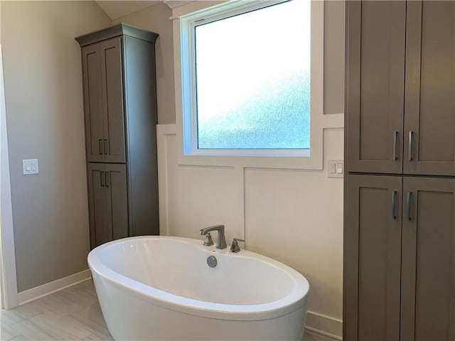 bathroom featuring a freestanding tub and baseboards