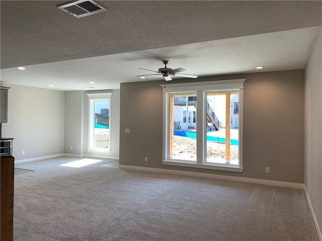 carpeted spare room with recessed lighting, baseboards, visible vents, and a textured ceiling