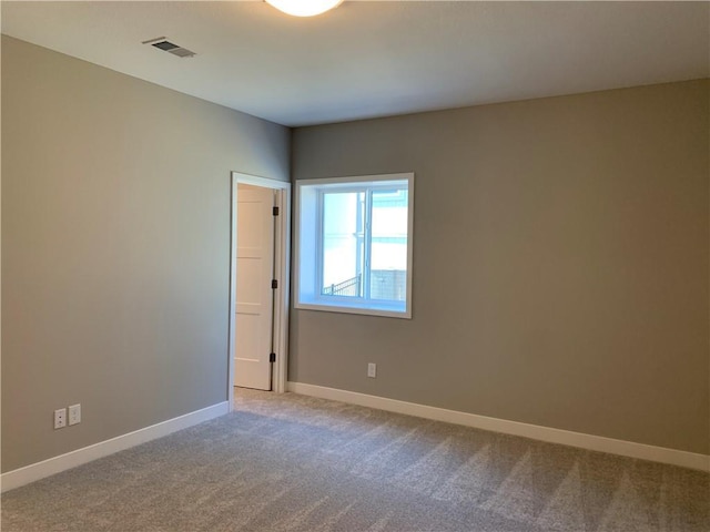 empty room featuring visible vents, baseboards, and carpet