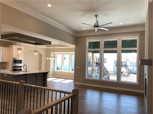 kitchen featuring ornamental molding, stainless steel appliances, light countertops, dark wood-type flooring, and white cabinetry