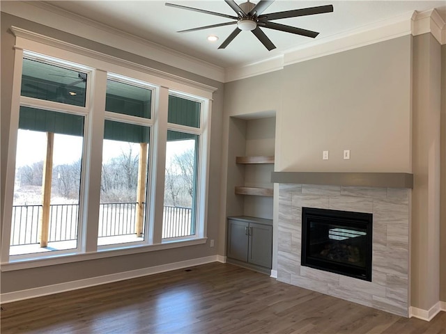 unfurnished living room featuring built in shelves, a healthy amount of sunlight, dark wood-style floors, and crown molding