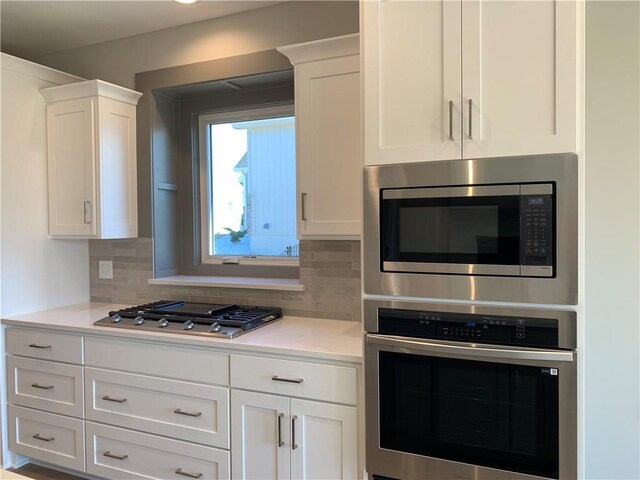 kitchen with white cabinetry, decorative backsplash, light countertops, and appliances with stainless steel finishes