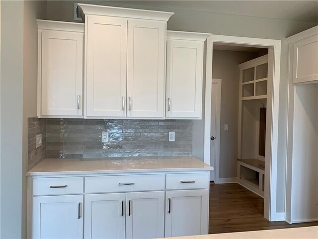 kitchen featuring dark wood-type flooring, white cabinetry, light countertops, decorative backsplash, and baseboards