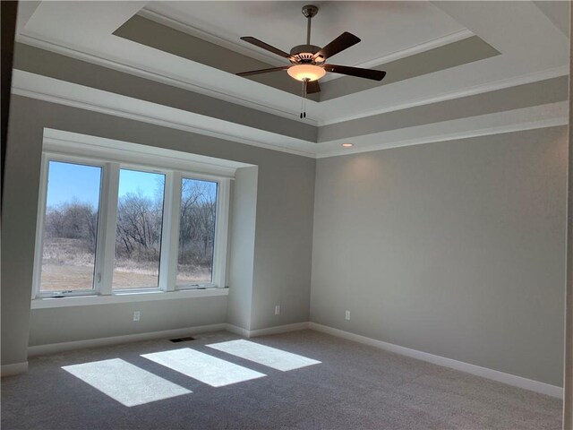 carpeted spare room with a tray ceiling, baseboards, and ornamental molding