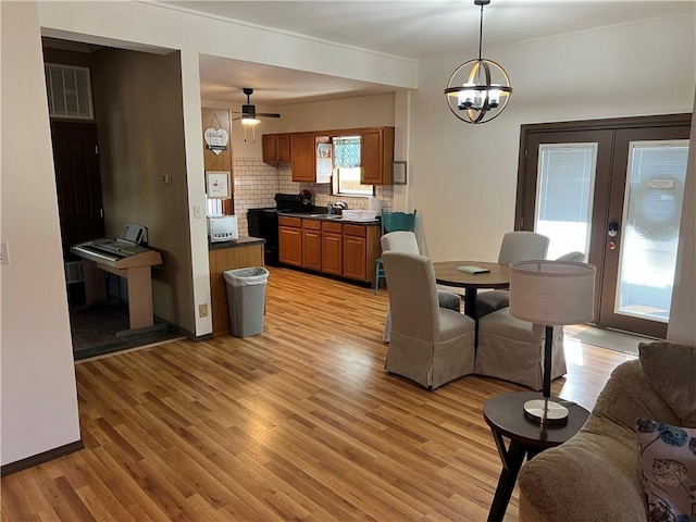 dining room with sink, light hardwood / wood-style flooring, and ceiling fan with notable chandelier