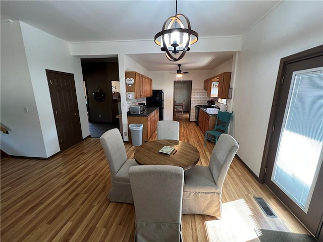 dining space featuring ceiling fan with notable chandelier and light wood-type flooring