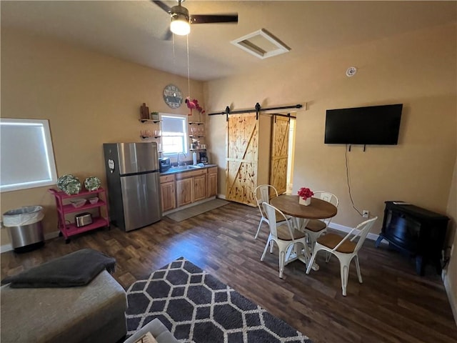 dining room featuring ceiling fan, dark hardwood / wood-style floors, sink, and a barn door