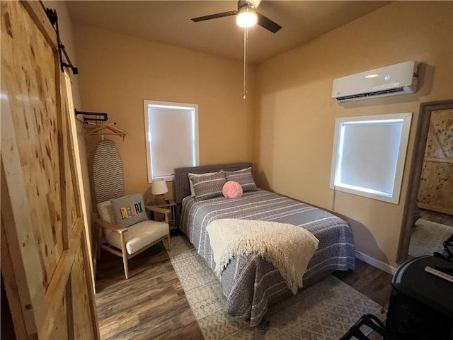 bedroom with hardwood / wood-style floors, a wall mounted AC, a barn door, and ceiling fan