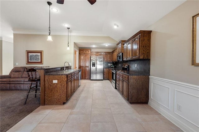 kitchen with a kitchen breakfast bar, pendant lighting, a kitchen island with sink, light tile patterned floors, and appliances with stainless steel finishes