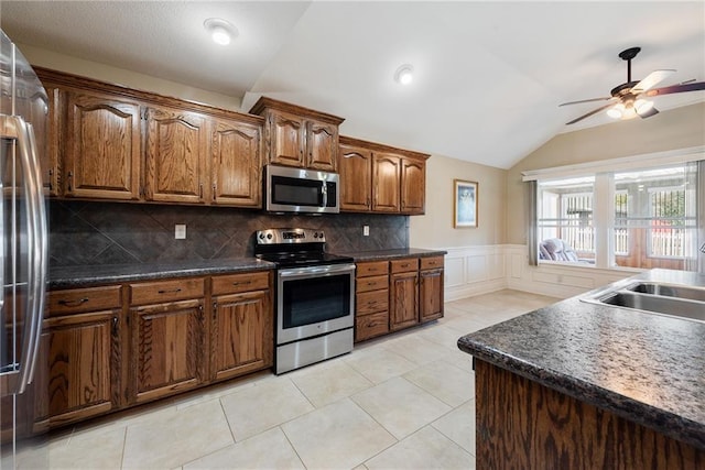 kitchen featuring backsplash, stainless steel appliances, vaulted ceiling, ceiling fan, and sink