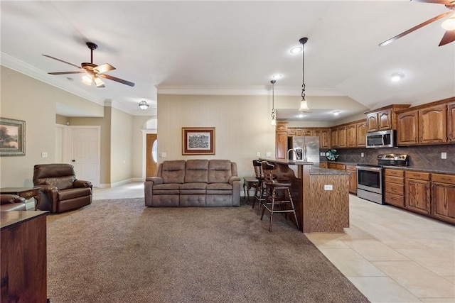 kitchen featuring a breakfast bar, backsplash, light carpet, hanging light fixtures, and stainless steel appliances