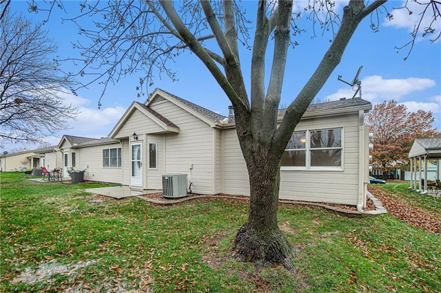 back of property with a lawn, cooling unit, and a patio area