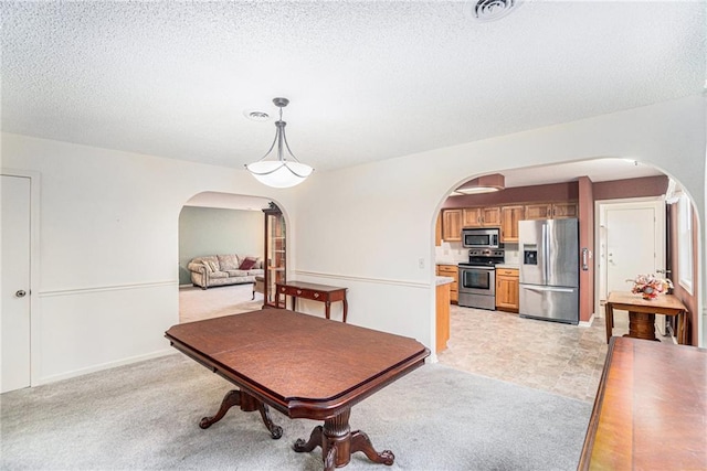 dining space with light colored carpet and a textured ceiling