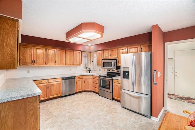 kitchen with light stone counters, a textured ceiling, and appliances with stainless steel finishes