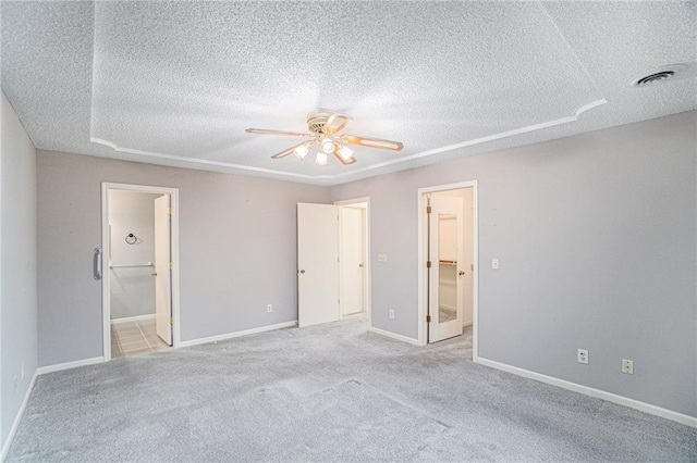 unfurnished bedroom featuring a textured ceiling, a walk in closet, and connected bathroom