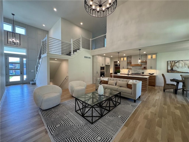 living room with hardwood / wood-style flooring, sink, a chandelier, and a high ceiling