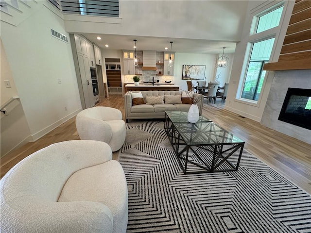 living room featuring hardwood / wood-style floors, sink, a high ceiling, and a fireplace