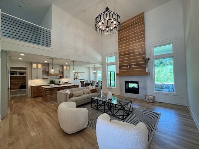 living room with a chandelier, a high ceiling, and light wood-type flooring