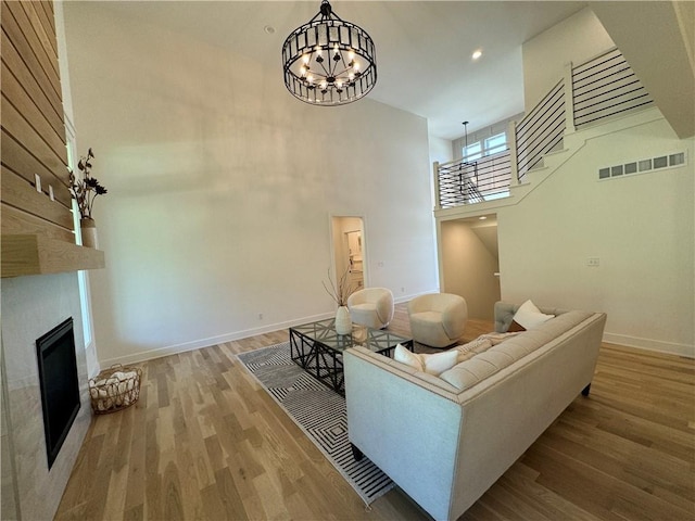 living room with a towering ceiling, an inviting chandelier, and hardwood / wood-style floors