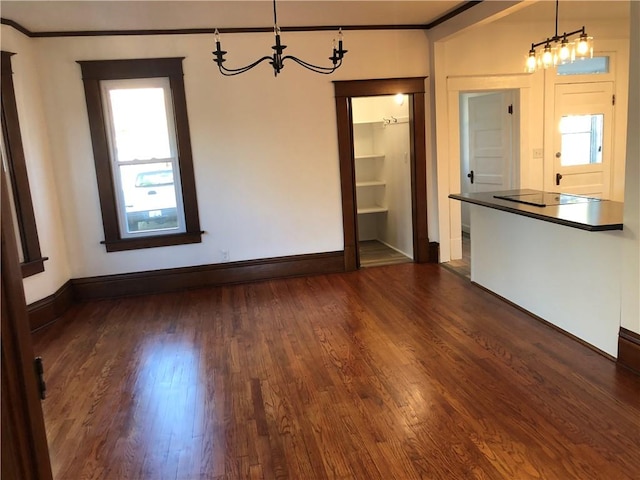 interior space with ornamental molding, a notable chandelier, and dark hardwood / wood-style floors