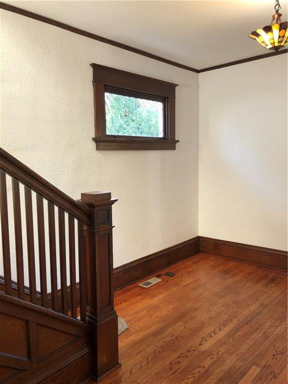 stairway featuring crown molding, hardwood / wood-style flooring, and a notable chandelier