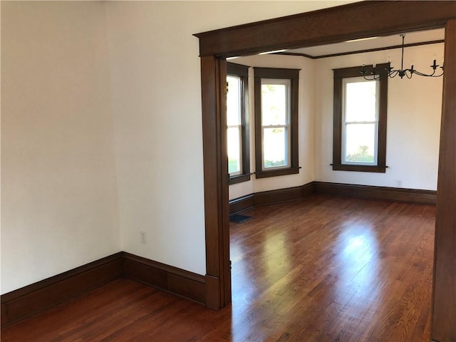 empty room featuring a chandelier and dark hardwood / wood-style flooring