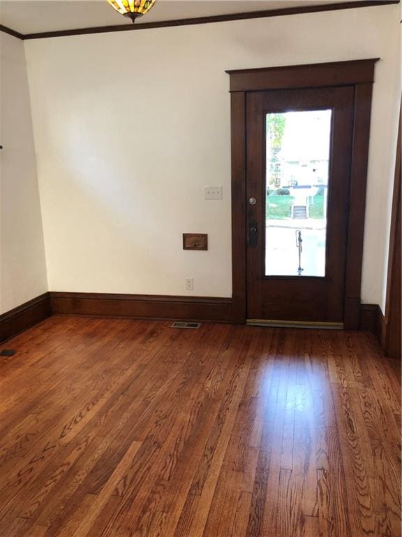 entryway with ornamental molding and dark wood-type flooring