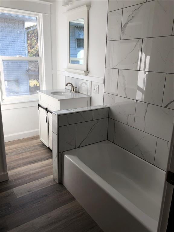 bathroom with a bathing tub, hardwood / wood-style floors, and vanity