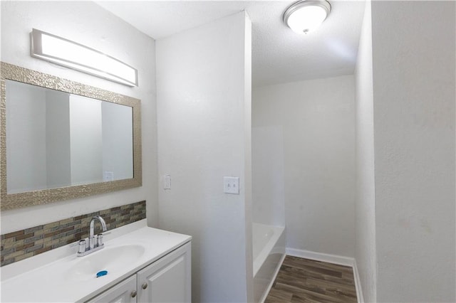 bathroom featuring vanity, tasteful backsplash, wood-type flooring, and a washtub