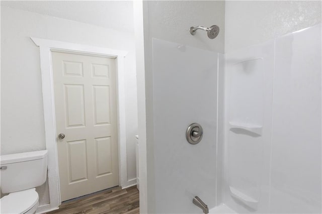 bathroom featuring toilet, a shower, and wood-type flooring