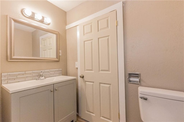 bathroom with vanity, toilet, and tasteful backsplash