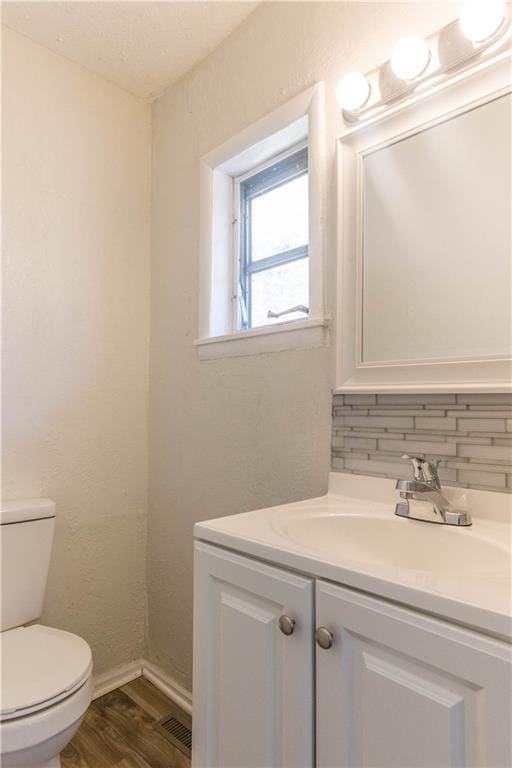 bathroom with vanity, toilet, hardwood / wood-style flooring, and decorative backsplash