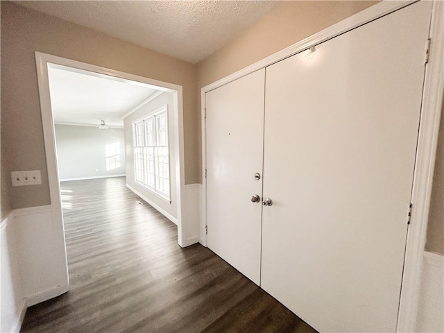 corridor with a textured ceiling and dark wood-type flooring