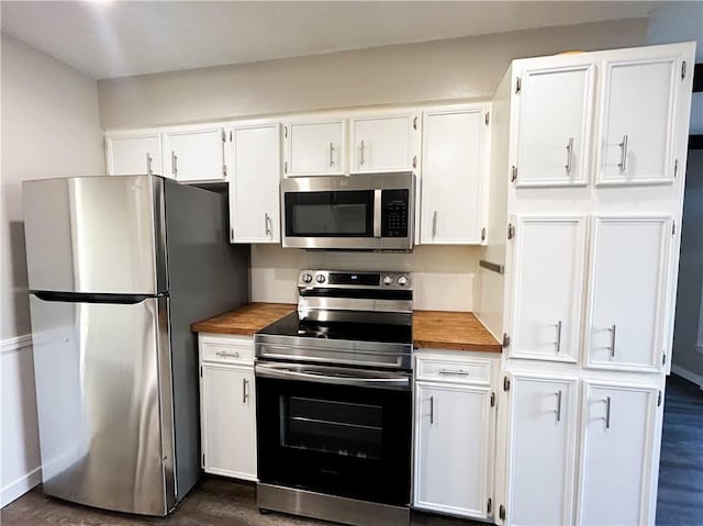 kitchen with white cabinets, dark hardwood / wood-style floors, appliances with stainless steel finishes, and wooden counters