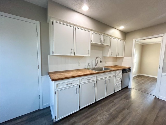 kitchen with white cabinets, butcher block countertops, stainless steel dishwasher, and sink