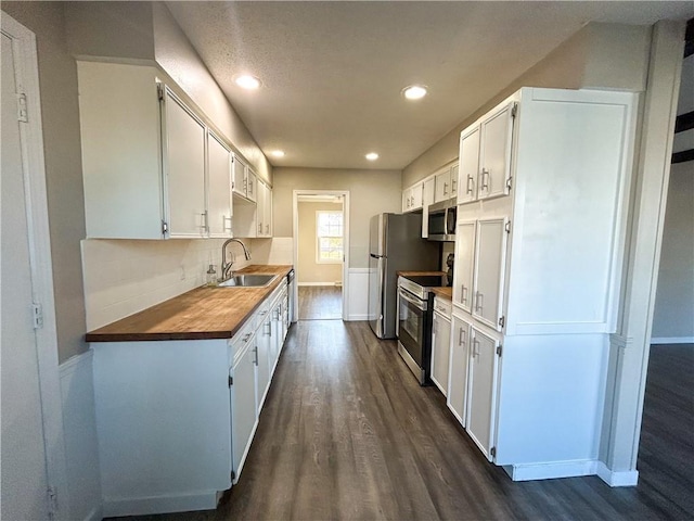 kitchen featuring wood counters, white cabinets, sink, appliances with stainless steel finishes, and dark hardwood / wood-style flooring