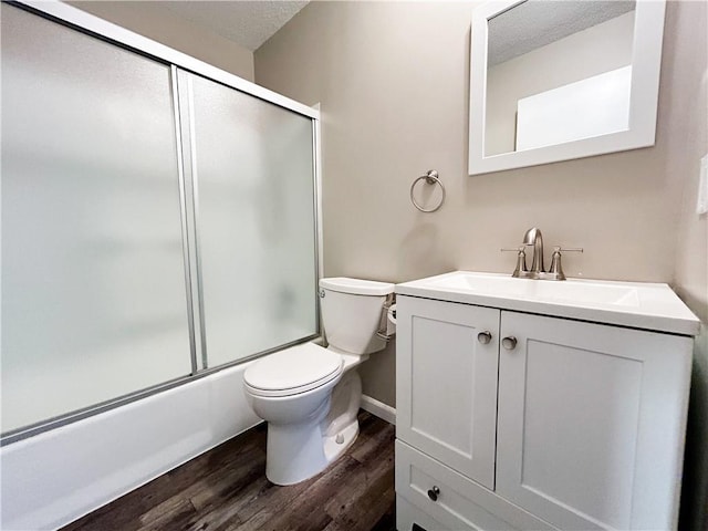 full bathroom featuring vanity, a textured ceiling, hardwood / wood-style flooring, enclosed tub / shower combo, and toilet