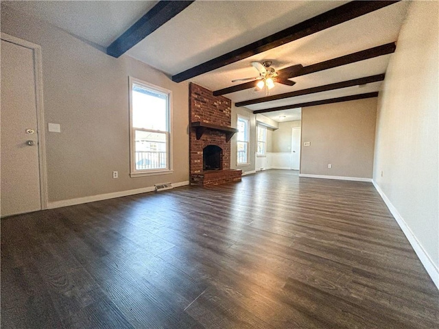 unfurnished living room featuring ceiling fan, beam ceiling, dark wood-type flooring, and a brick fireplace