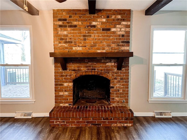 interior details featuring beamed ceiling, wood-type flooring, a textured ceiling, and a brick fireplace