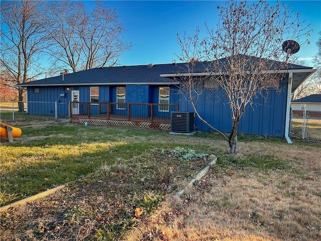 back of property with central AC unit and a lawn