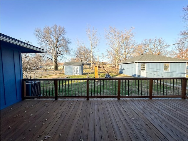 wooden terrace with a storage shed and a playground