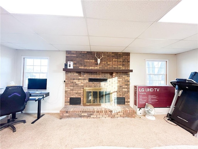 exercise room featuring a fireplace, carpet flooring, plenty of natural light, and a drop ceiling