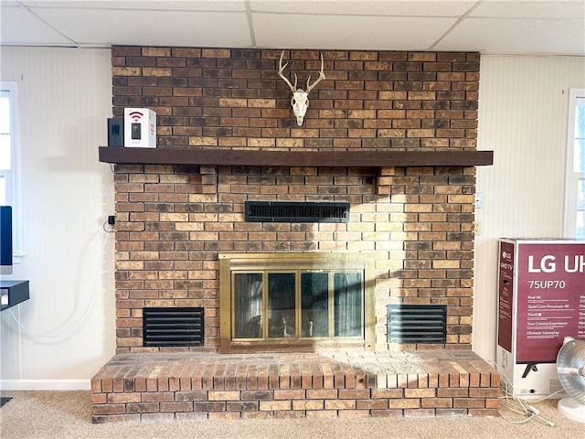 room details with a fireplace, carpet flooring, and a drop ceiling