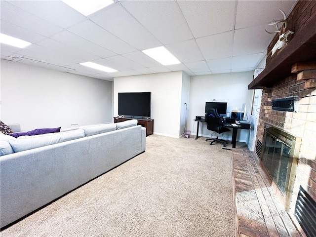 carpeted living room featuring a drop ceiling and a brick fireplace